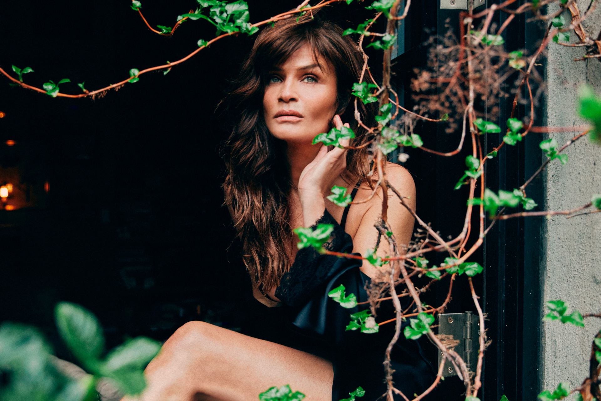 Woman in black robe sat surrounded by vines