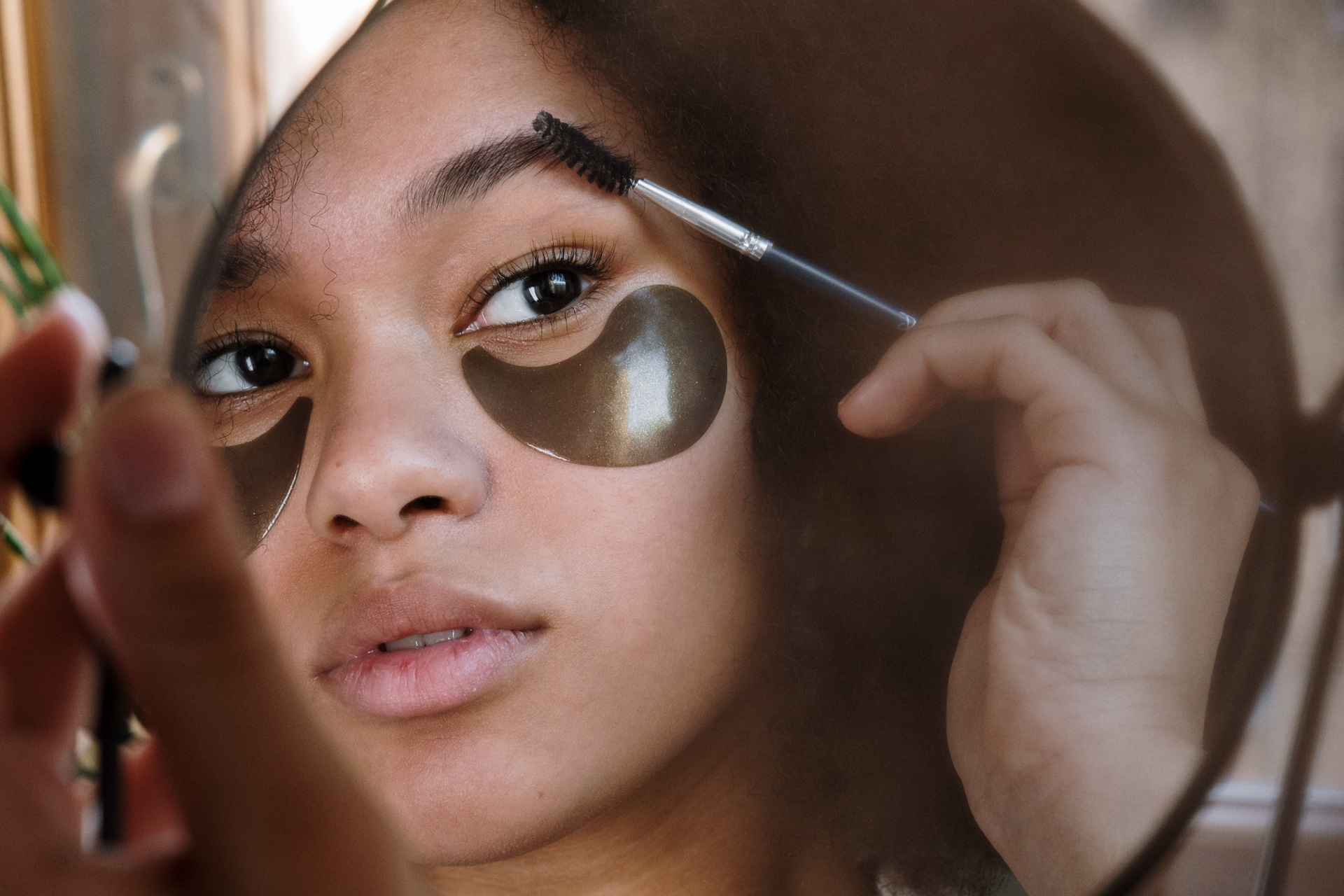 Woman brushing out eyebrows in mirror