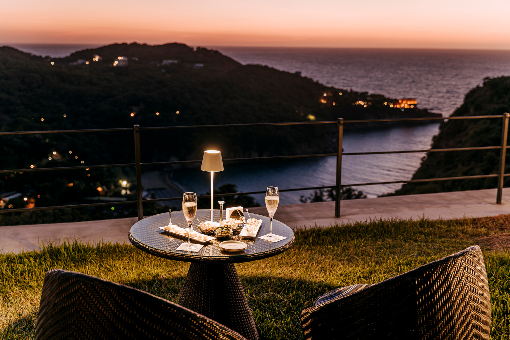 Outdoor table set with drink looking out to sea at night