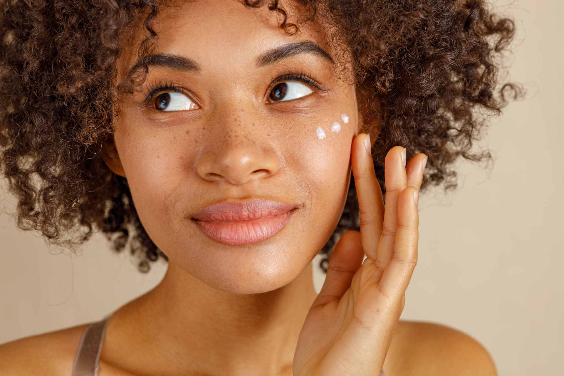 Woman putting dots of moisturiser on her face