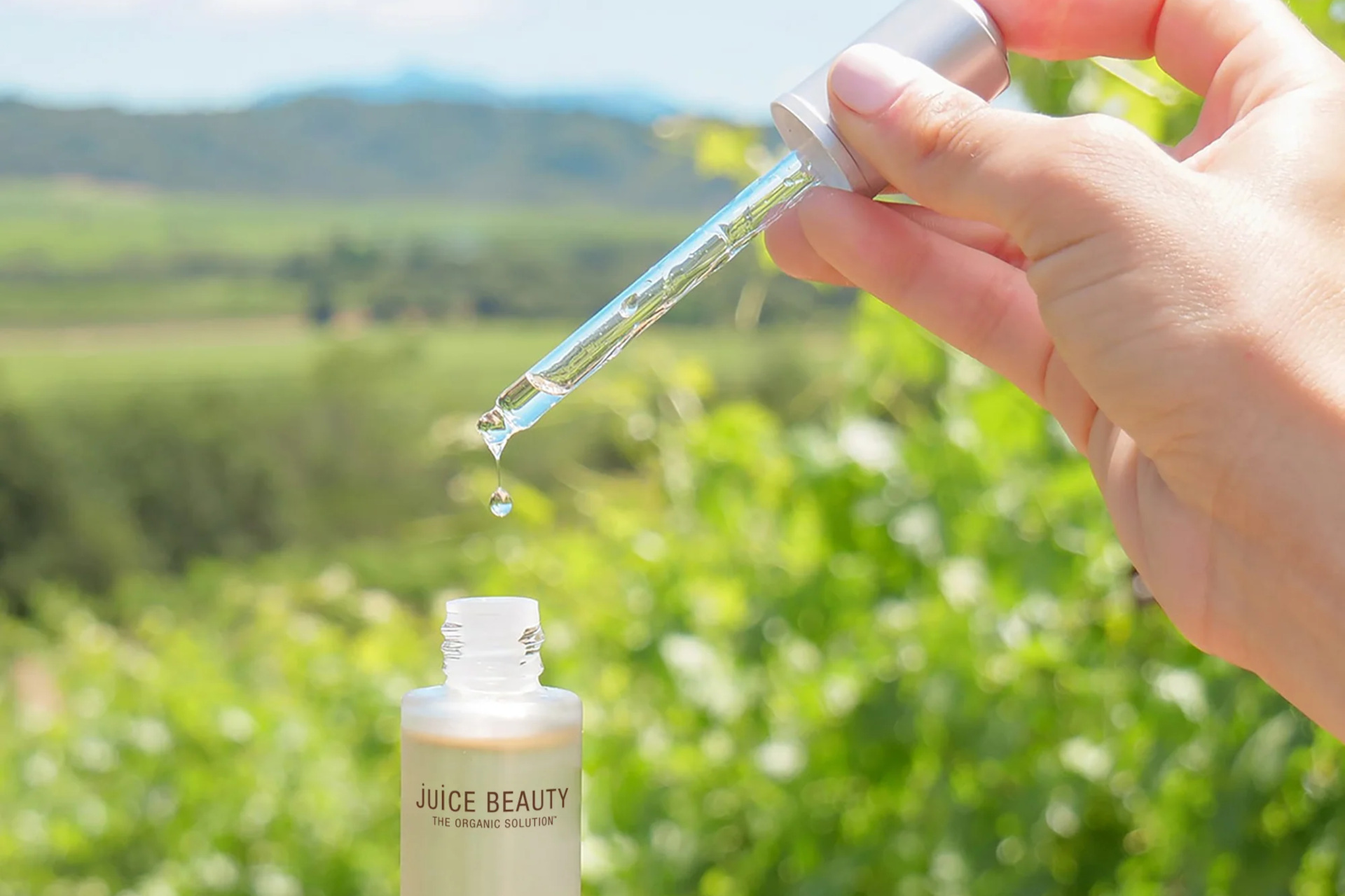 Hands holding serum bottle in front of field