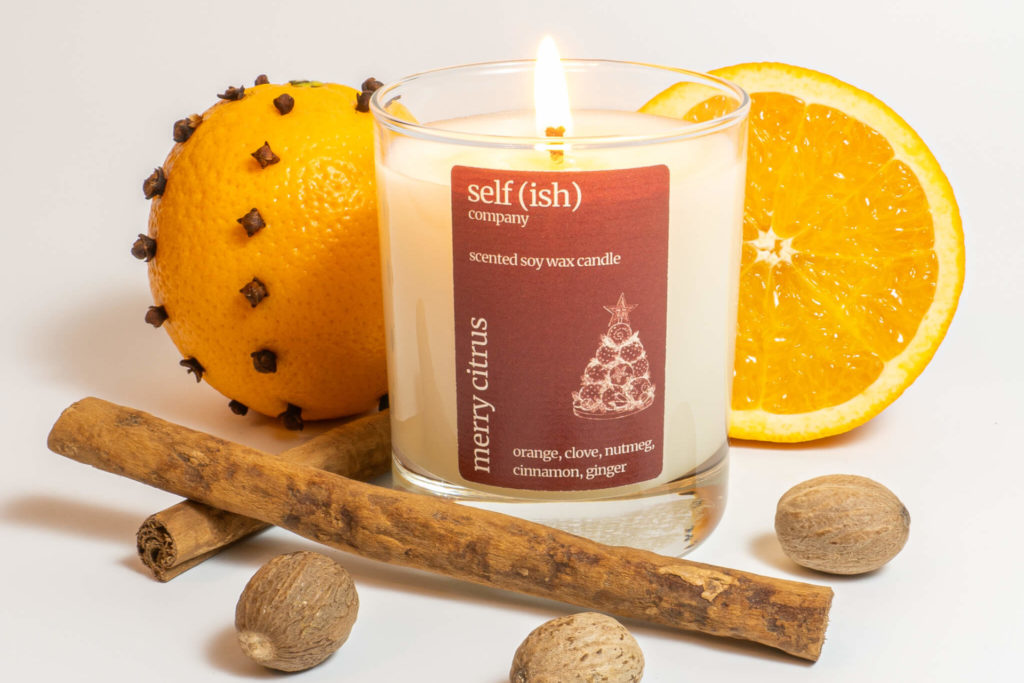 Candle surrounded by oranges and spices