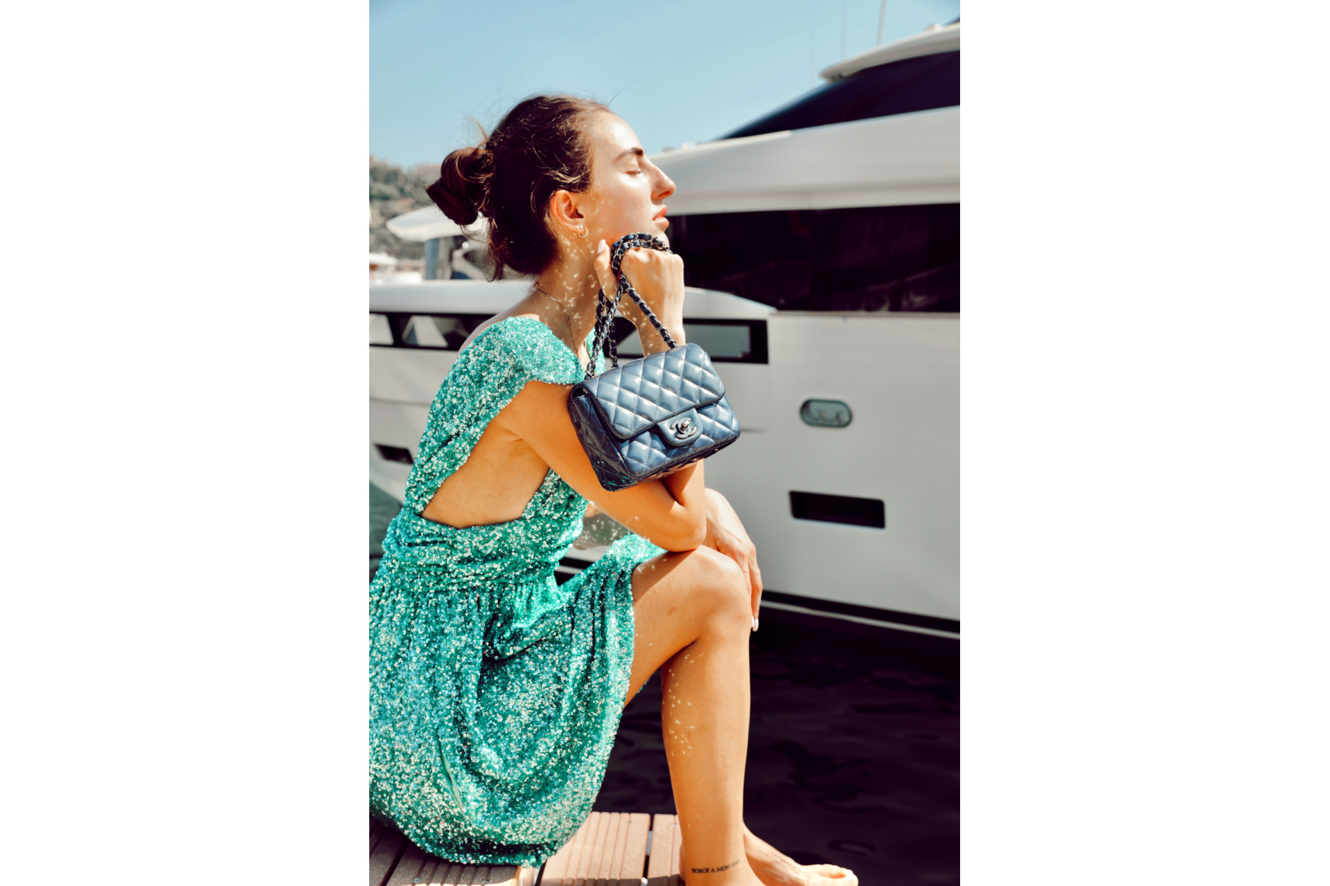 Qoman in green sequin dress holding black handbag