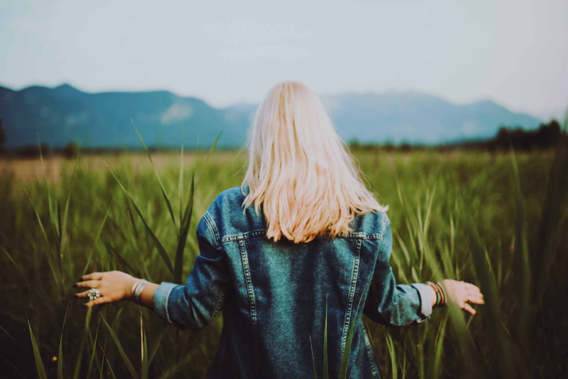 Woman with blonde hair walking through tall grass