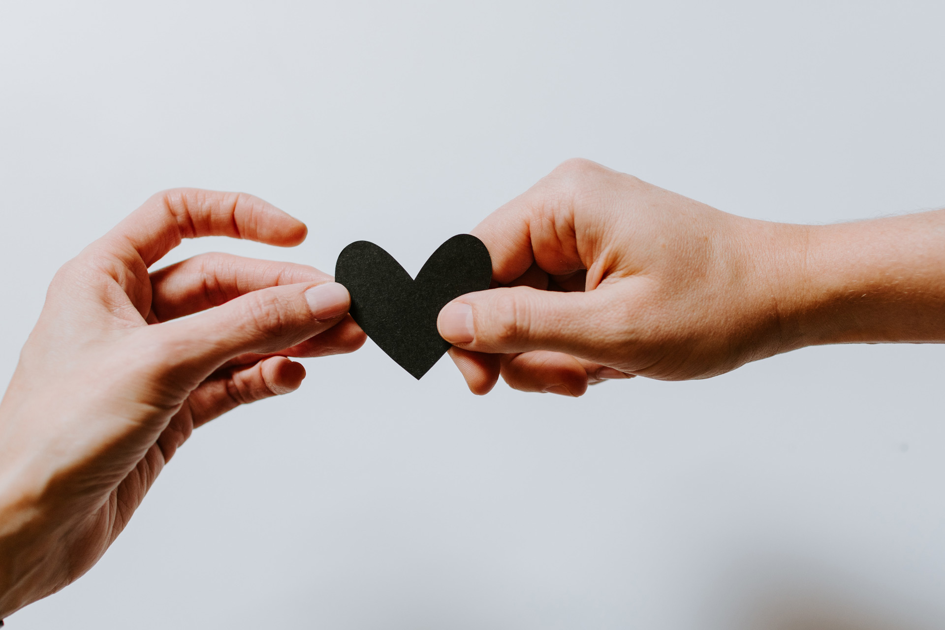 Hands holding black paper heart