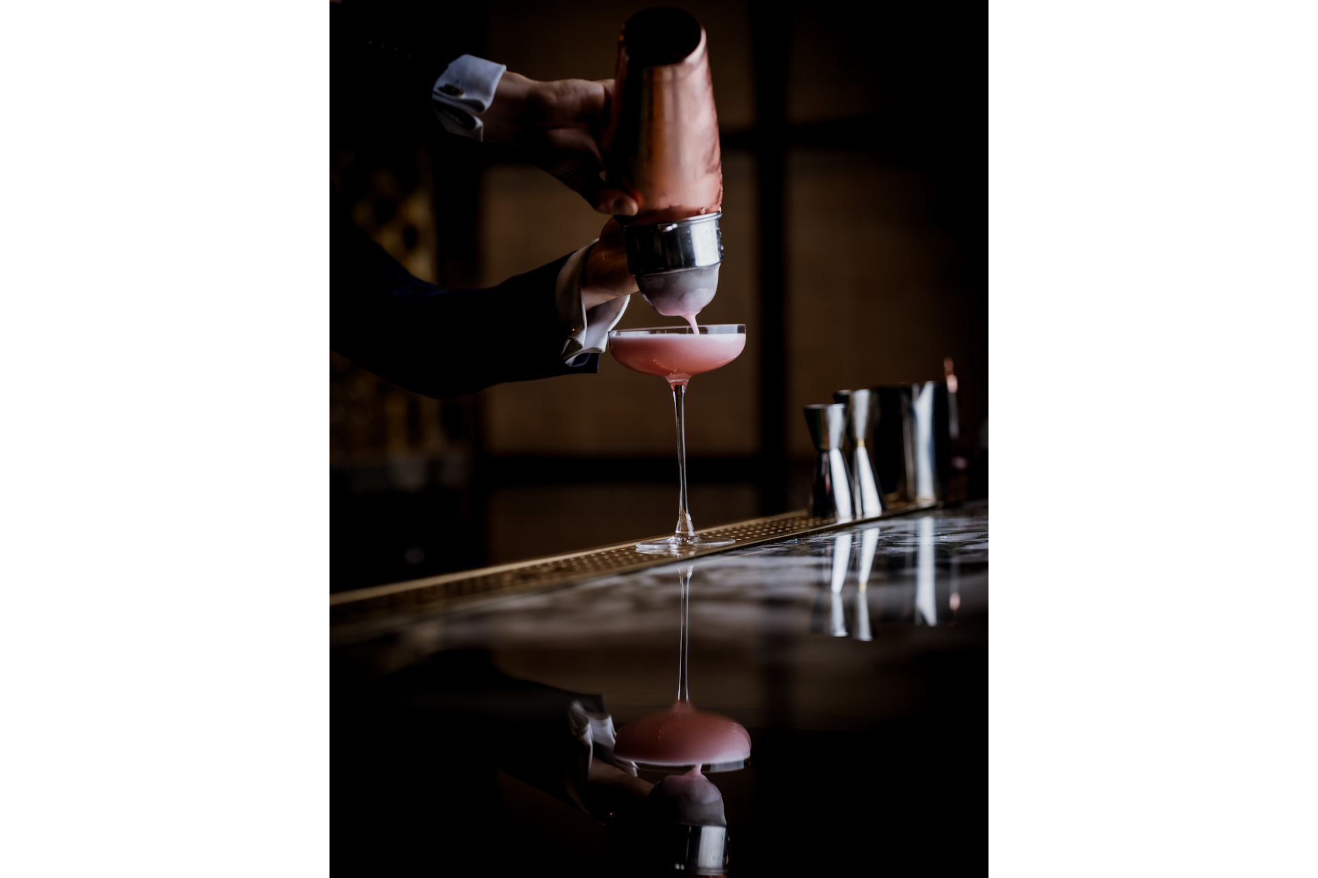 Cocktail being prepared in dark bar