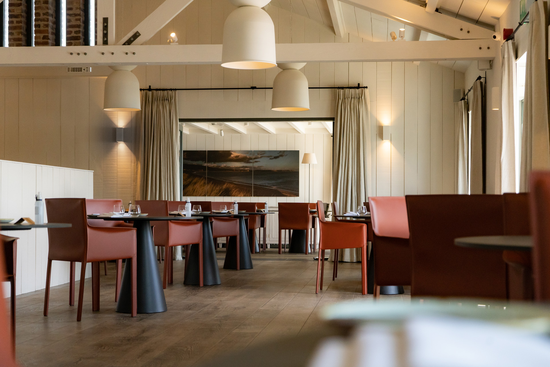 Interior of Beach House restaurant in Oxwich, with dark red chairs and vaulted ceilings