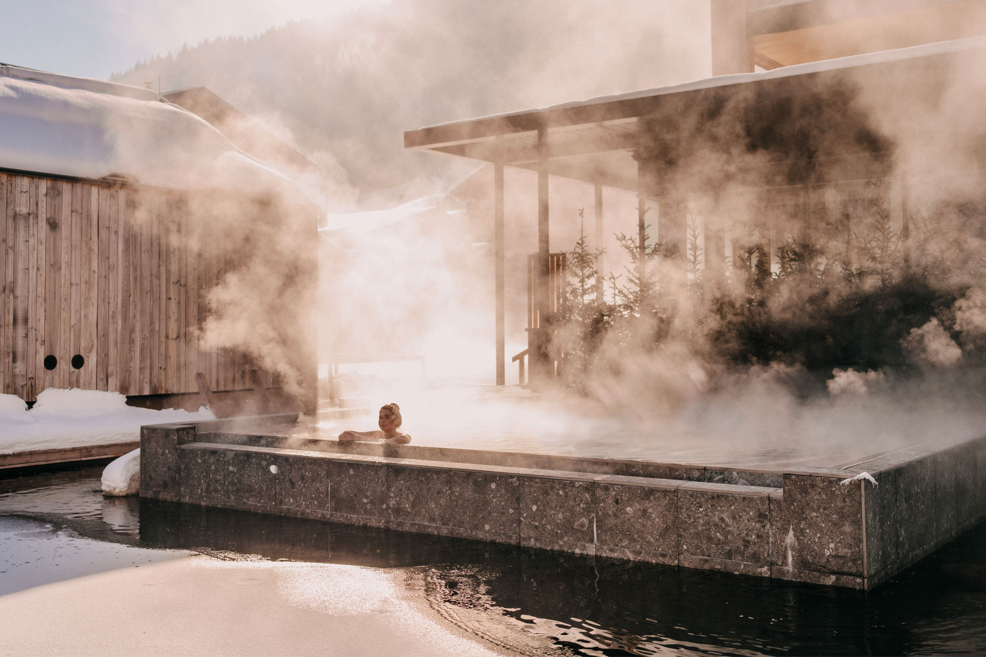 A woman in a steaming hot tub at Naturhotel Forsthofgut