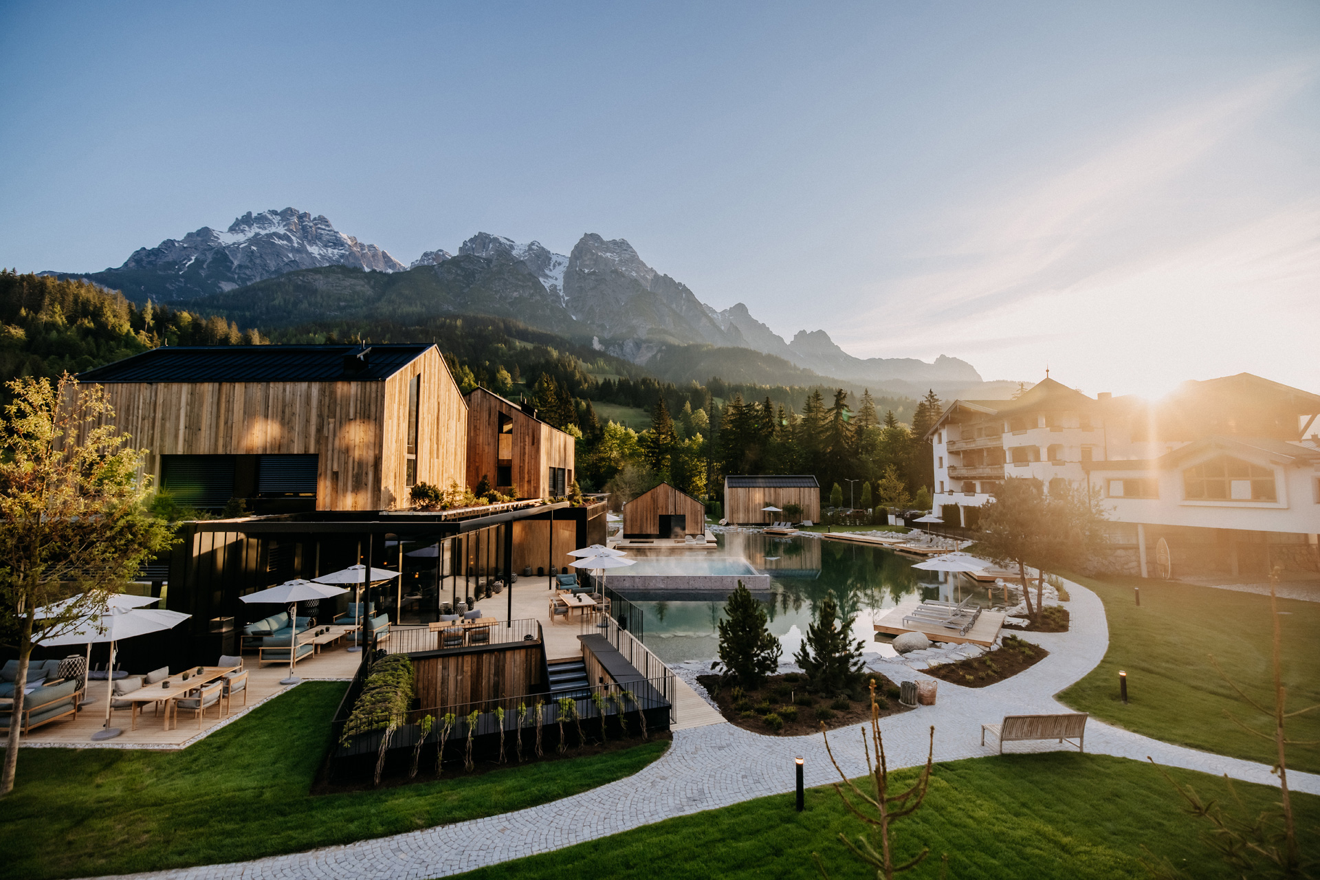 View of Forsthofgut hotel including wooden chalets, paths and the mountains