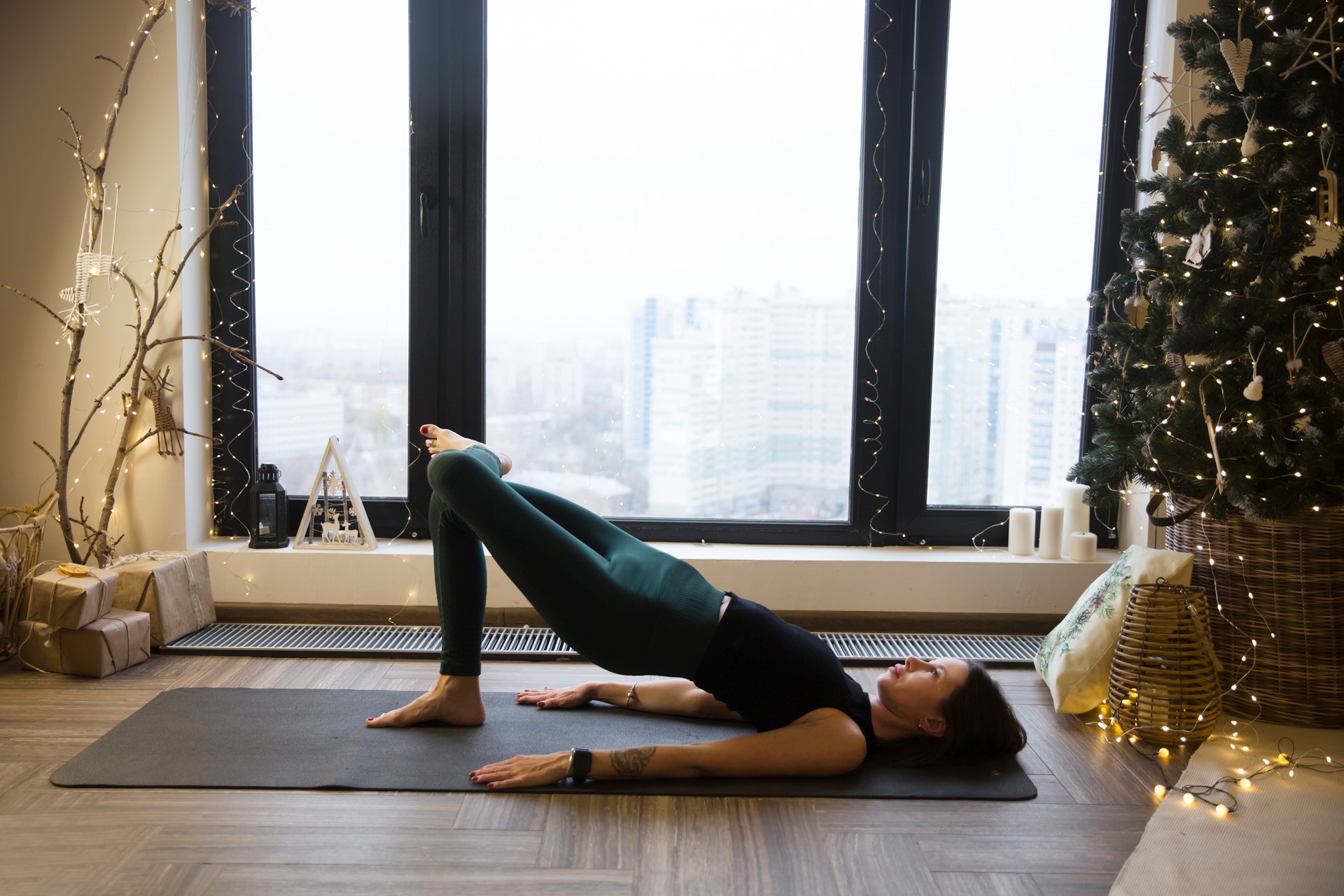 Woman doing a glute bridge next to a Christmas tree