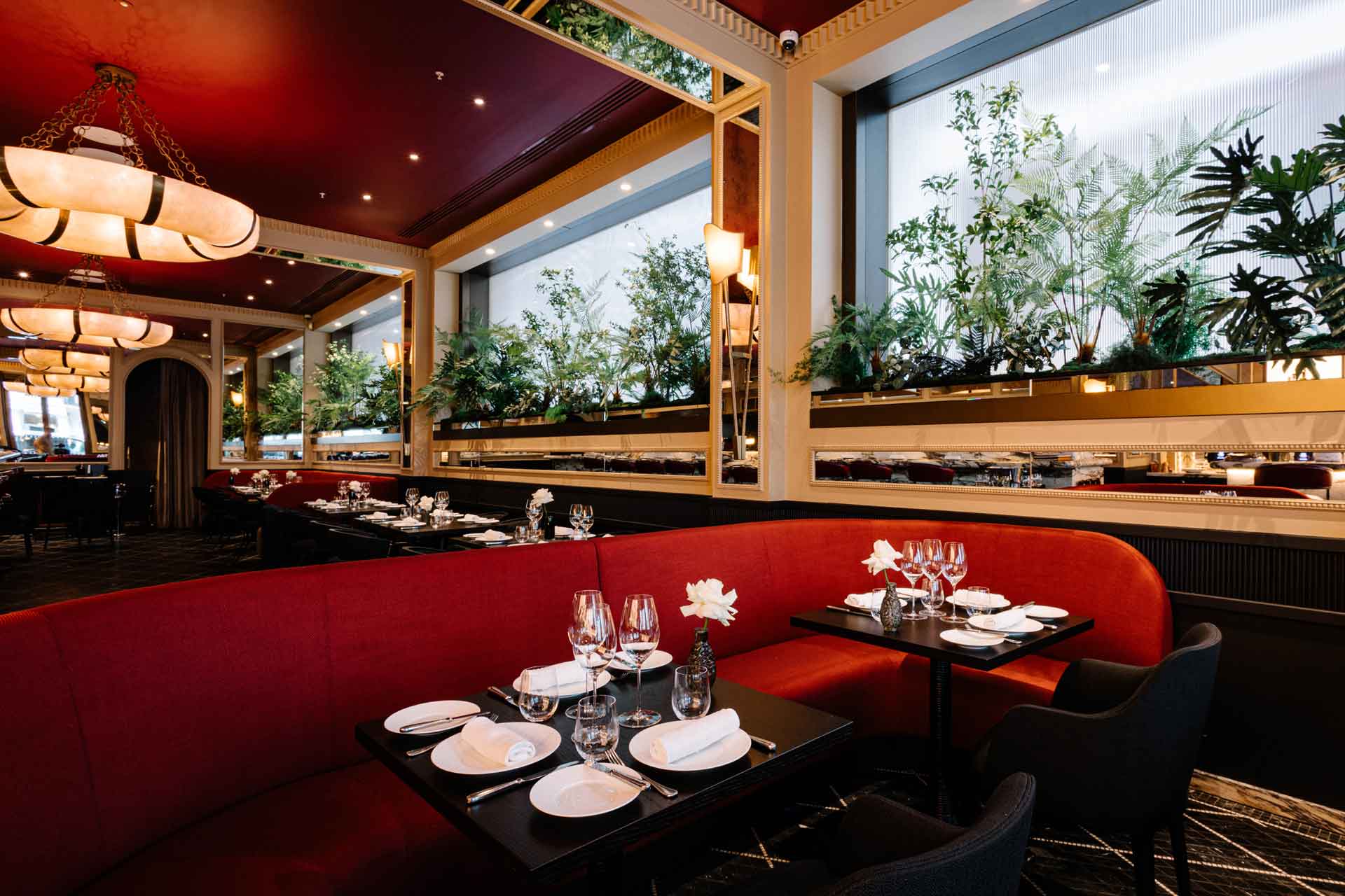 Restaurant with red plush seating, red ceilings and marble pendant lights