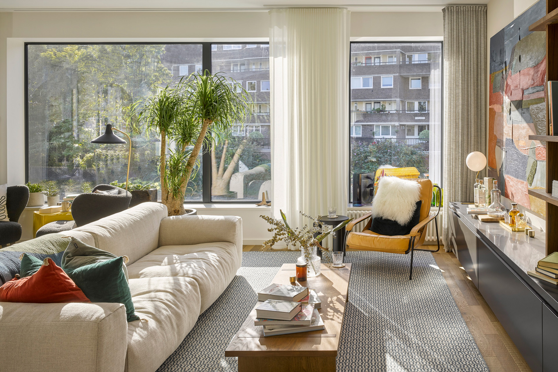 Apartment living room with cream furniture and red and yellow accents.