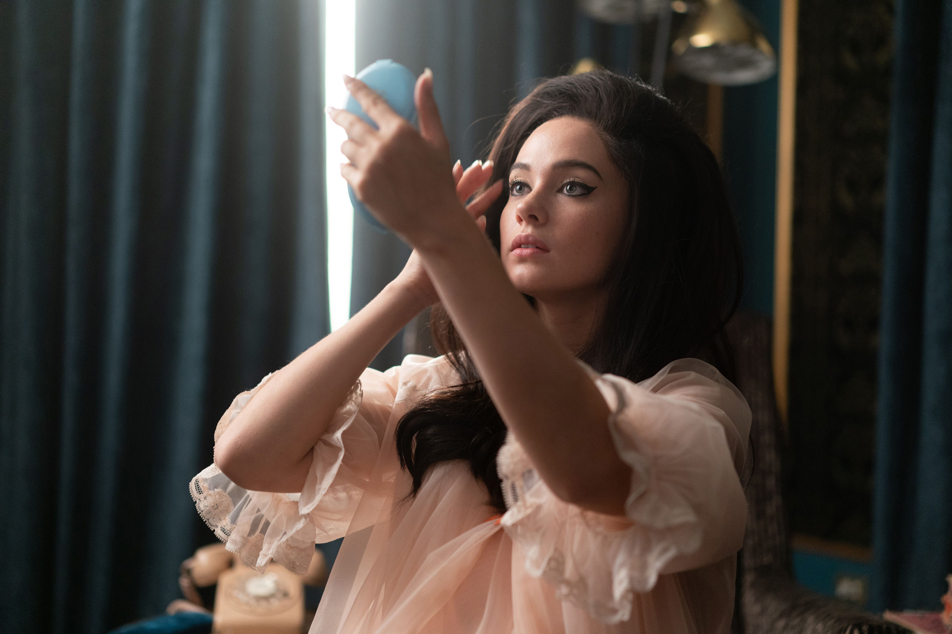 Cailee Spaeny as Priscilla Presley | woman with dark bouffant hair looking in hand mirror