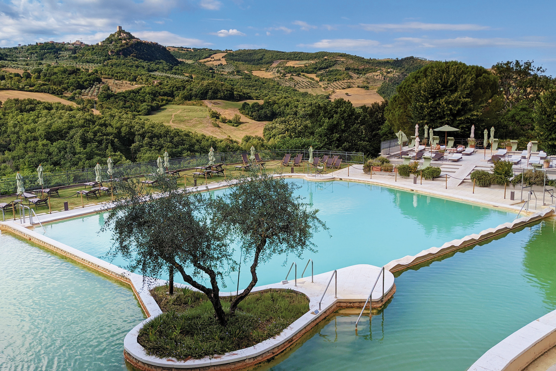 A hotel swimming pool surrounded by Tuscan hills