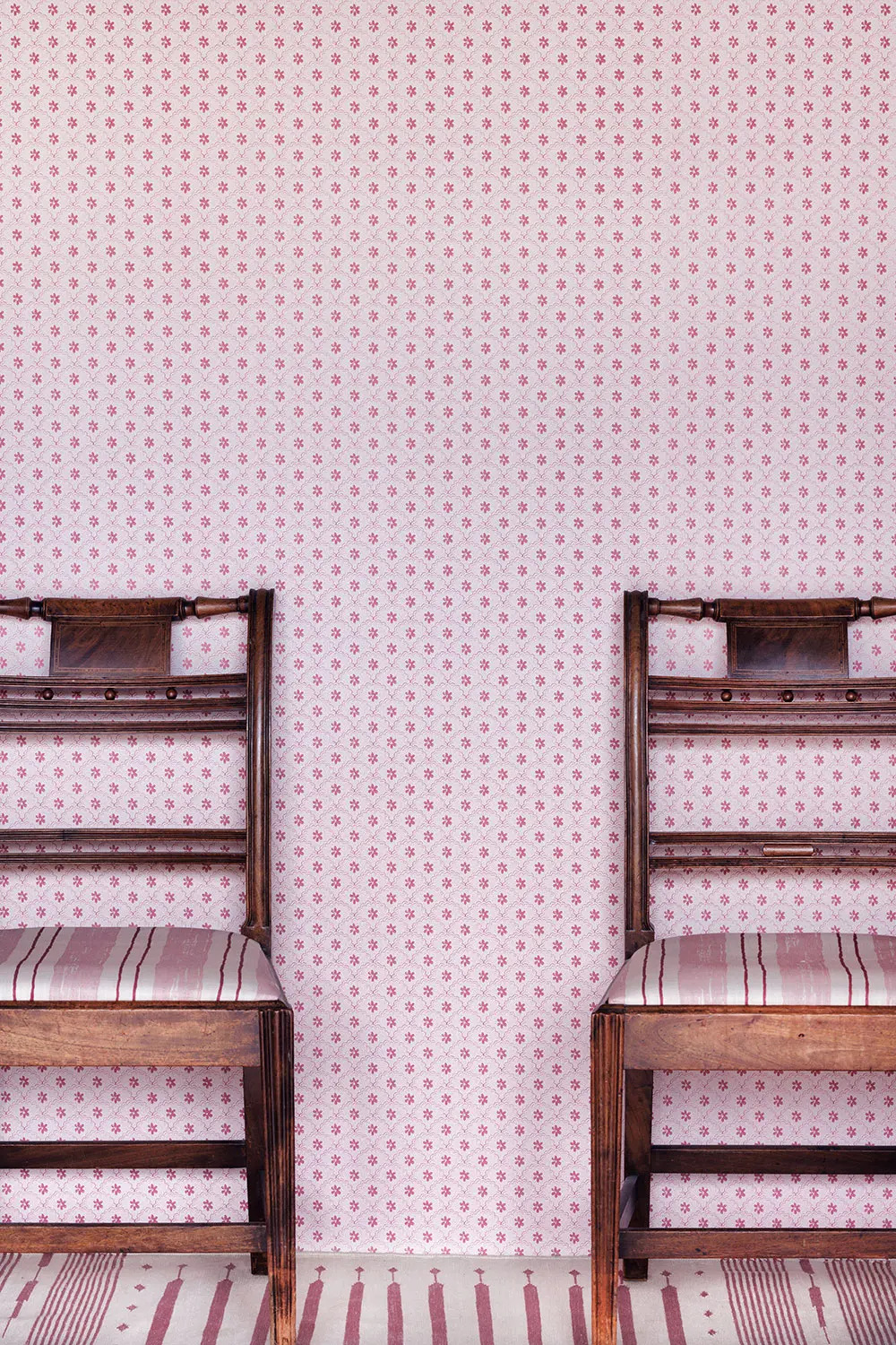 Wooden chairs in front of pink wallpaper
