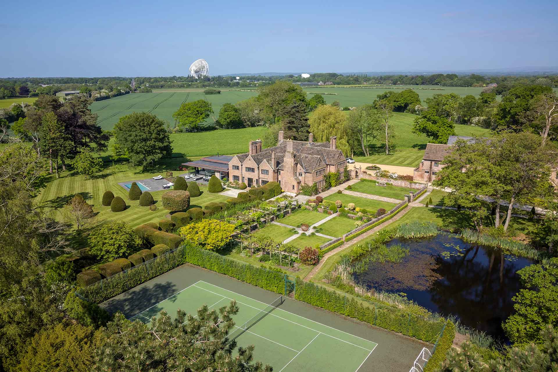 Aerial view of country manor with tennis court and box hedges