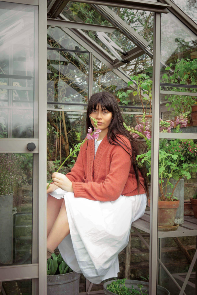 Woman in peach cardigan from British knitwear brand HERD