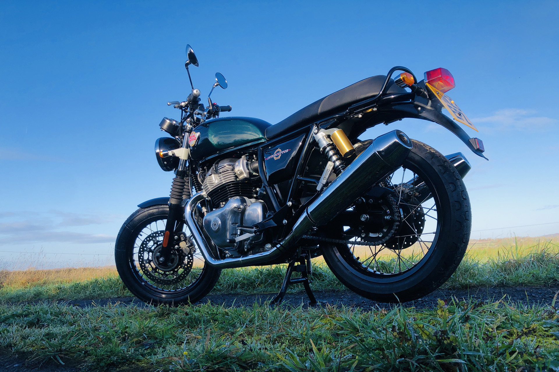 The Royal Enfield Interceptor against a blue sky in a field