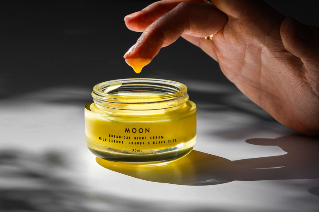 Finger dipping into tub of yellow-coloured cream