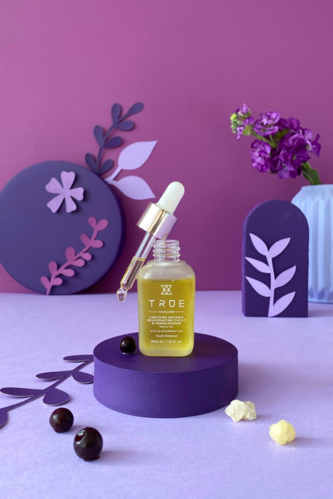 Facial serum bottle on purple background