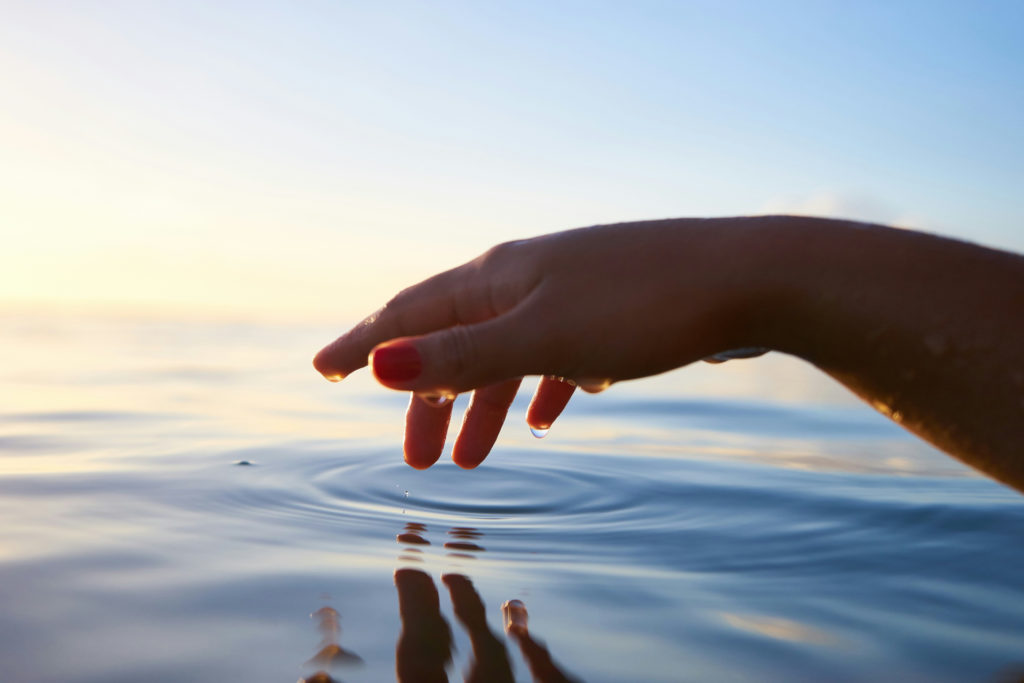 Hand touching water's surface - Wellness Trends 2024