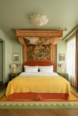 Pale green bedroom with yellow bedspread and a tapestry hanging over the bed