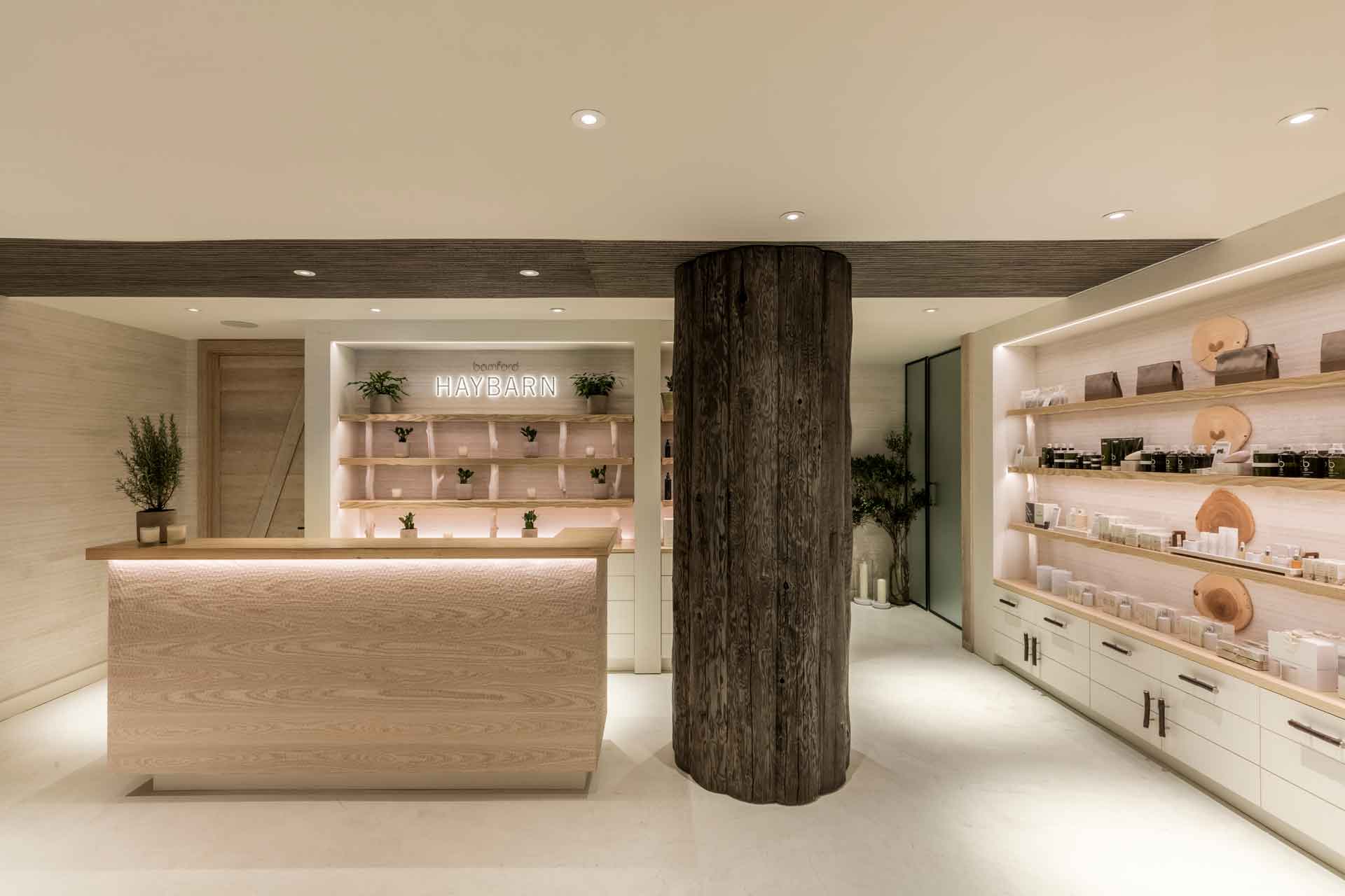 Spa with white surfaces, a central wooden beam and a shelf of products lining the wall