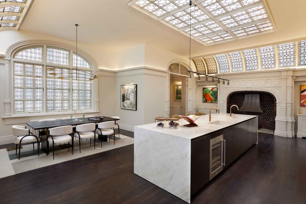 Modern kitchen with black cabinets, white marble surfaces and large windows