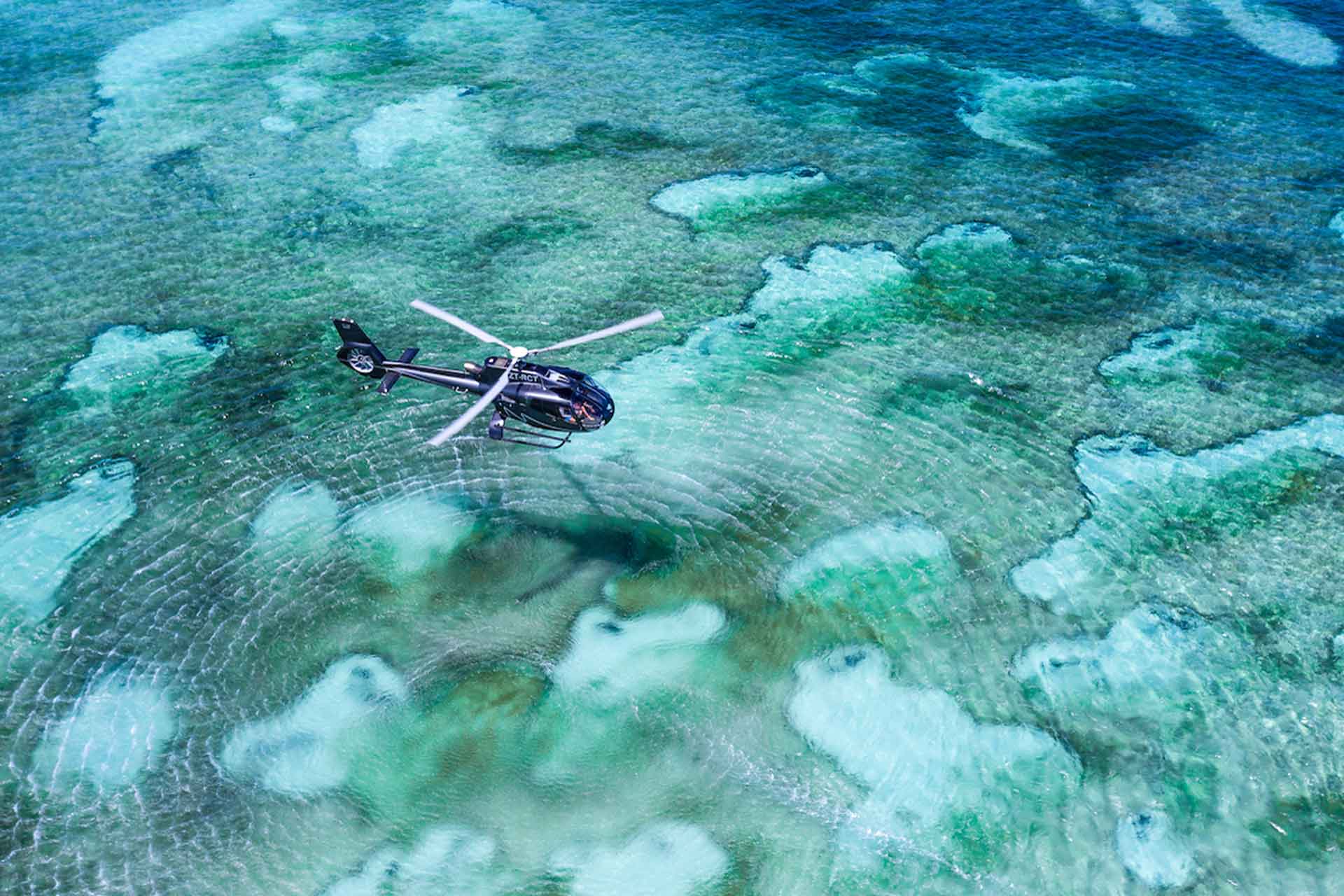 Aerial view of helicopter flying over the water surrounding Thanda Island