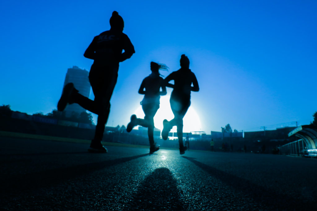 Silhouettes of people running on blue background