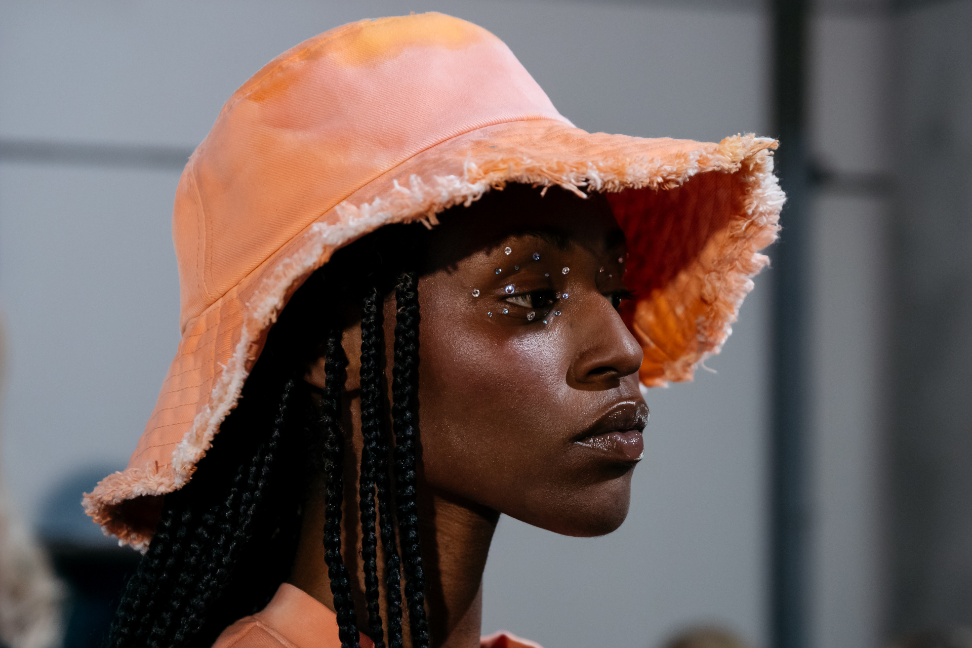 Woman in orange hat having rhinestones applied to her face