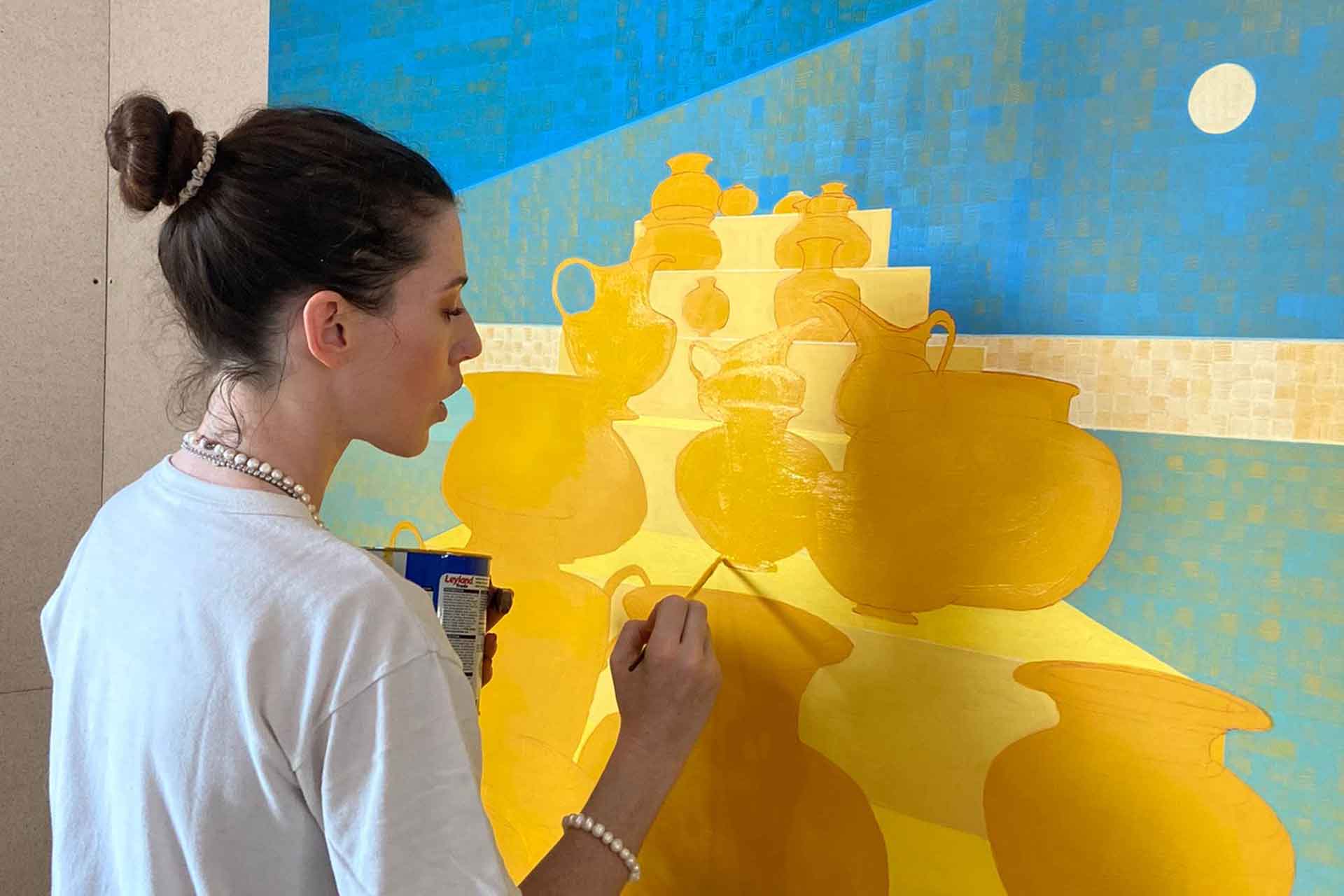Artist painting on a blue and yellow canvas