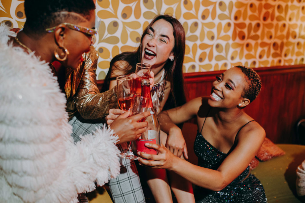 Woman sat together in party clothes with drinks