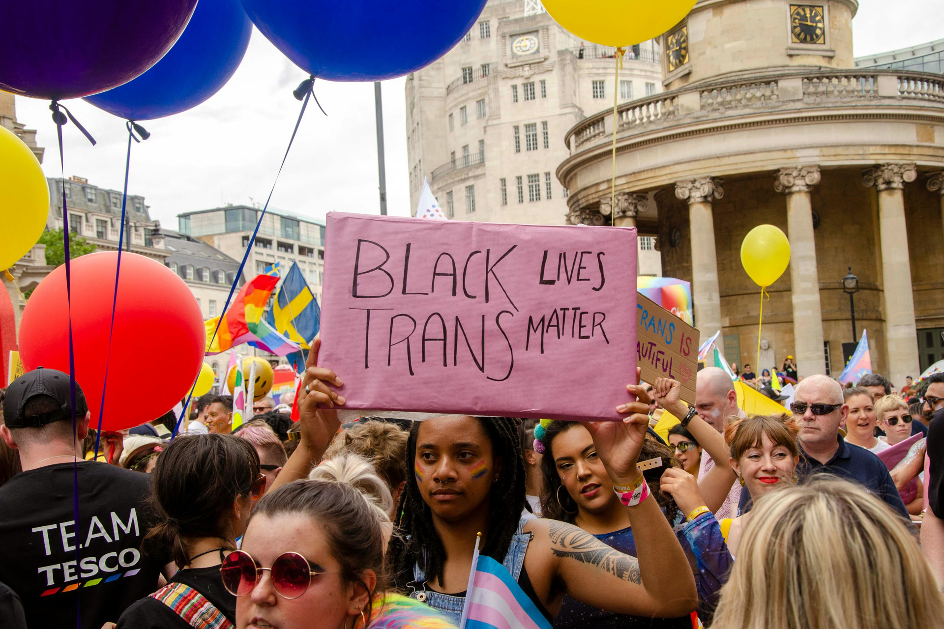 People on The Street Holding Signs and Balloons