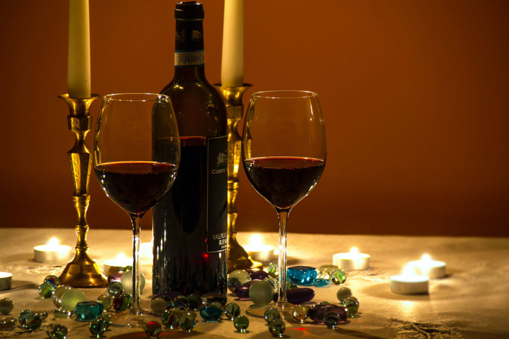 Two glasses of red wine on a candlelit table