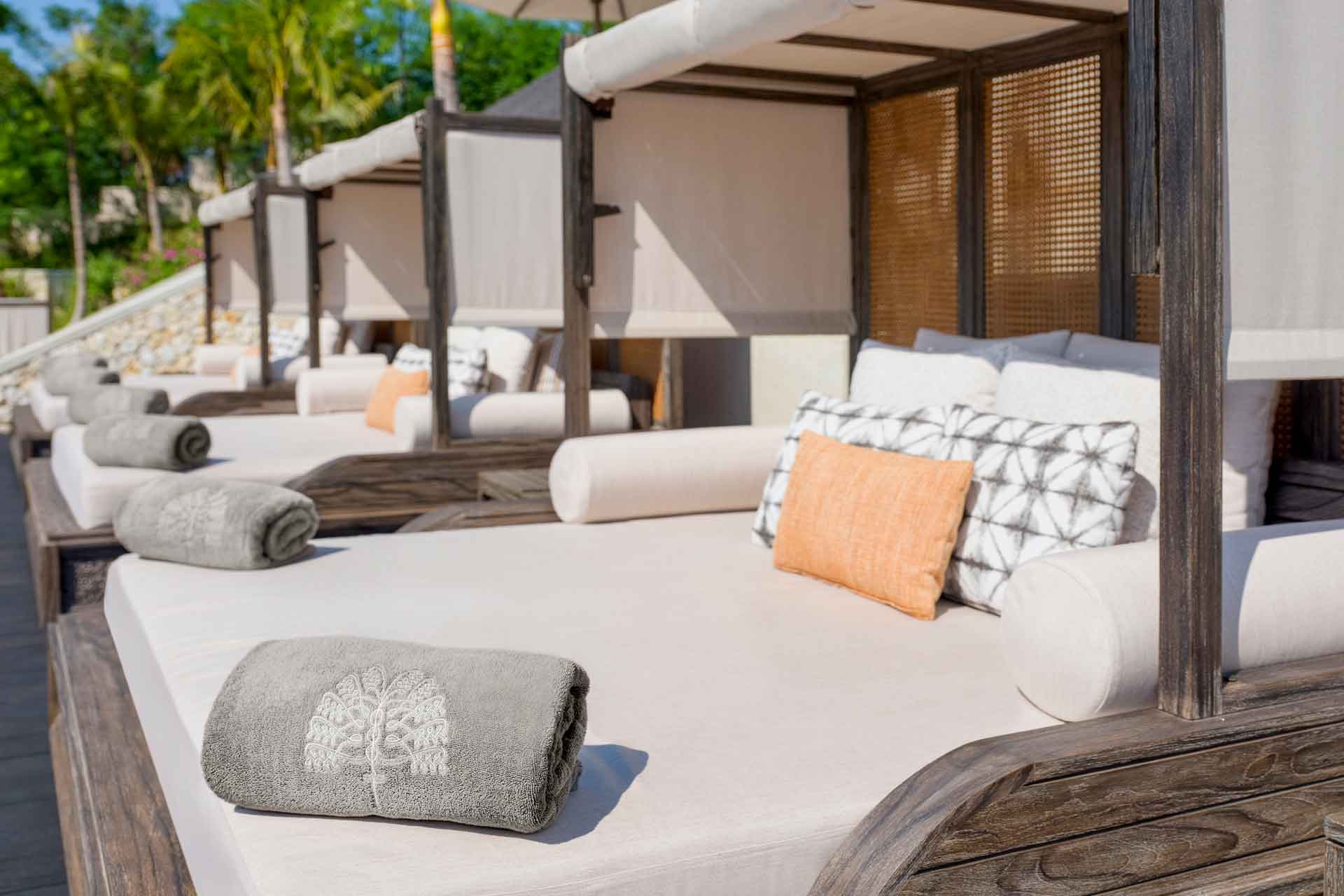 Pool cabanas at Raffles Bali, with grey towels and orange cushions
