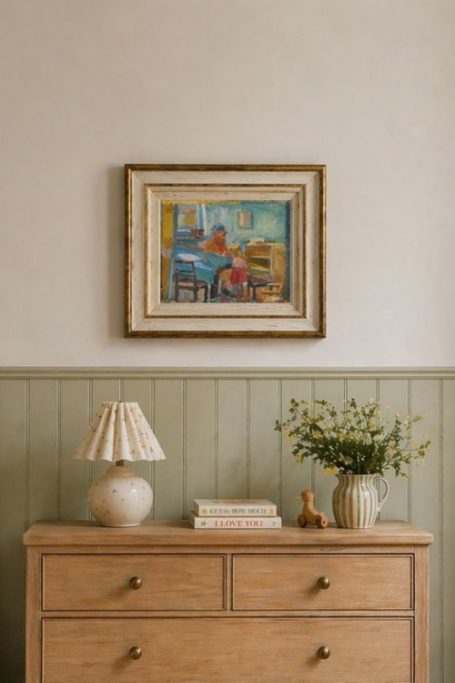 Painting on wall above green panelling and wooden drawers
