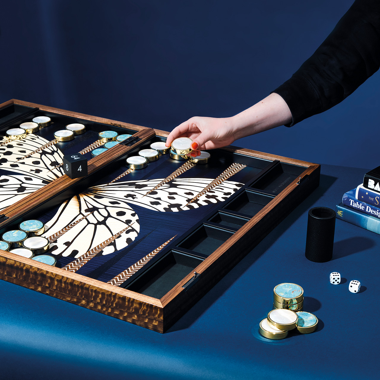A hand reaching to a board game with a butterfly on it