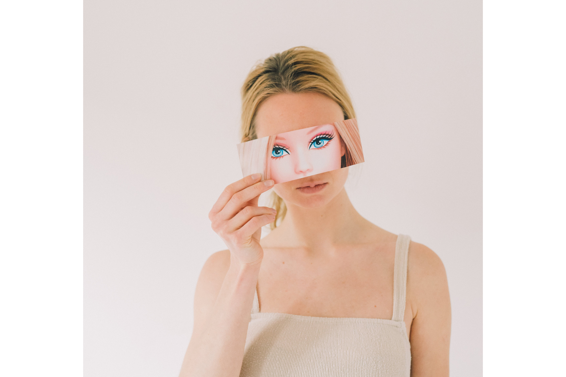 Blonde model holds picture of Barbie up to eyes