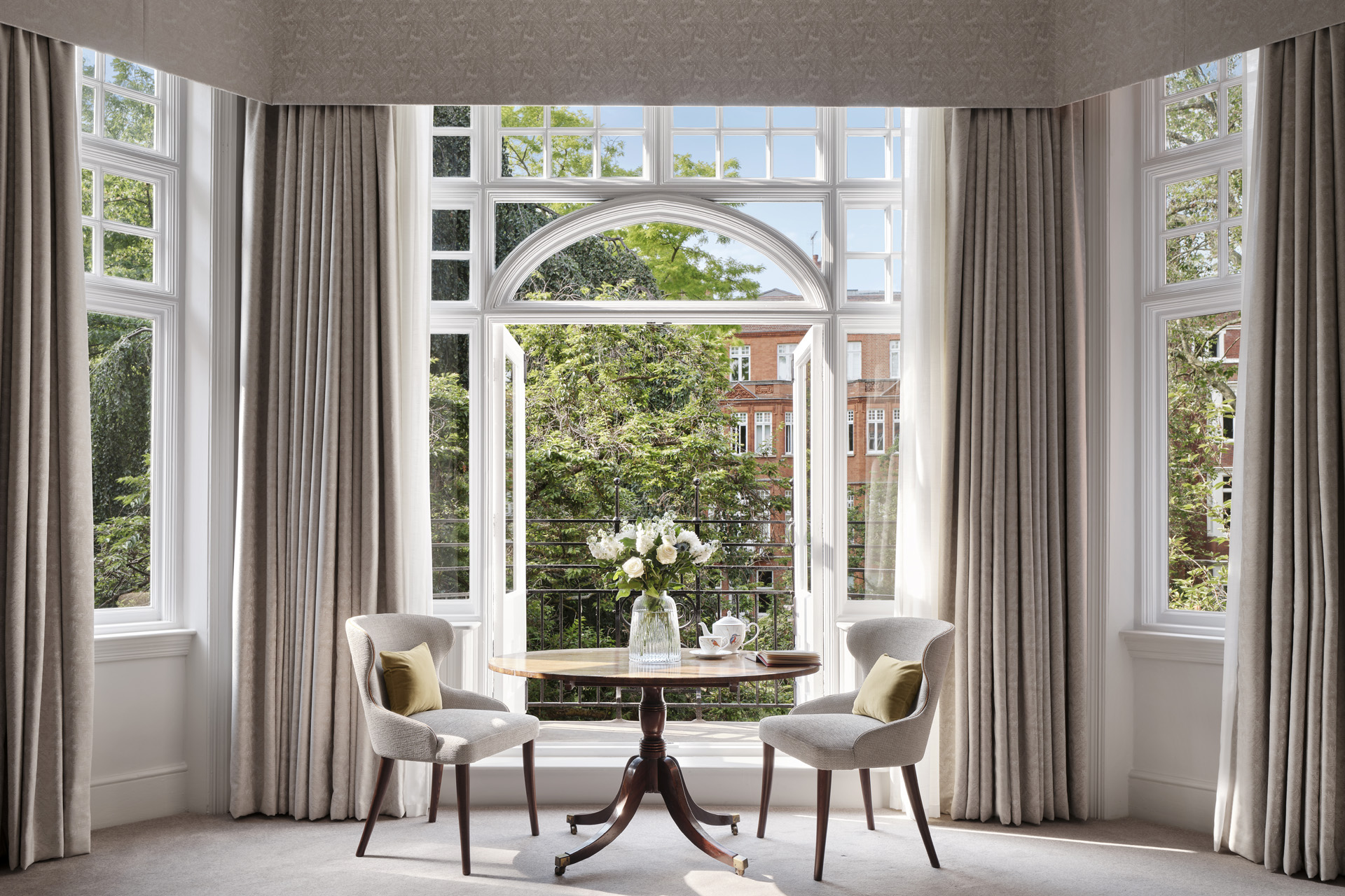 Two chairs beside a large open window overlooking the gardens