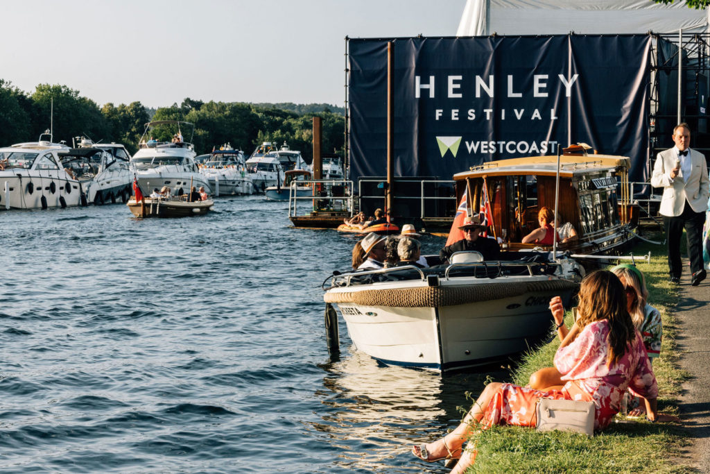 People sitting on the river bank at Henley Festival