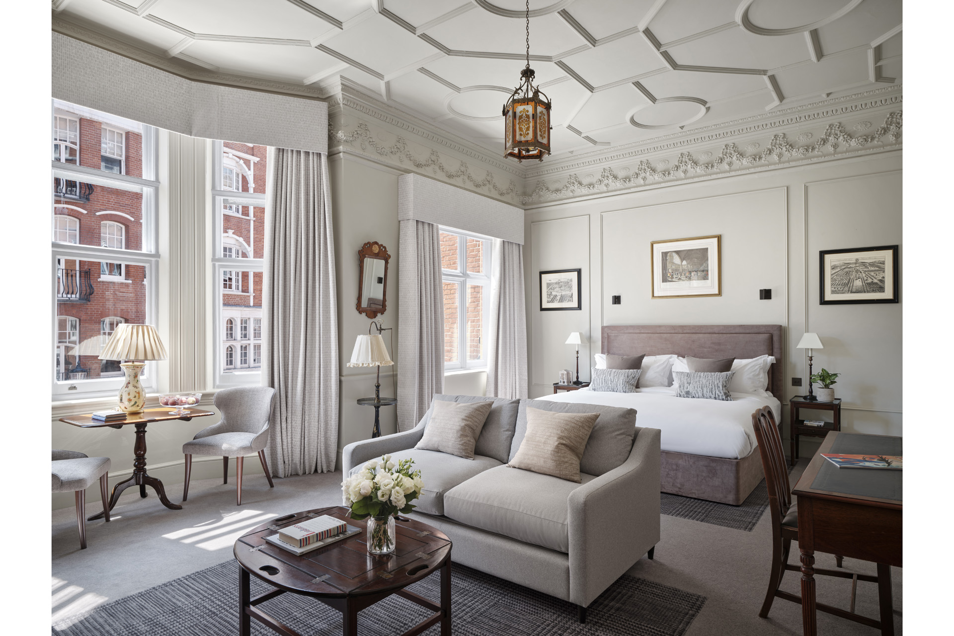 A large, light-filled bedroom with a bed and sofa overlooking the Chelsea streets