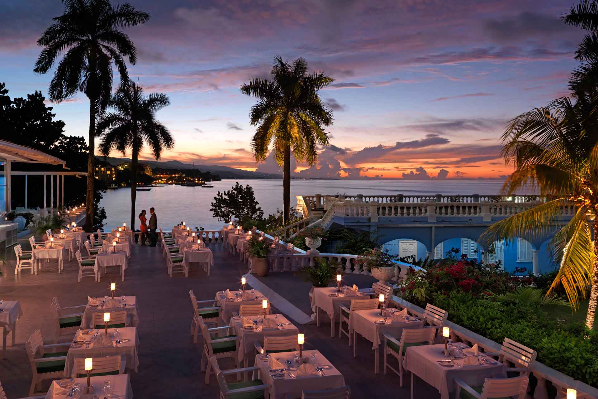 Beach dining at Jamaica Inn at sunset, with white tables and palm trees.