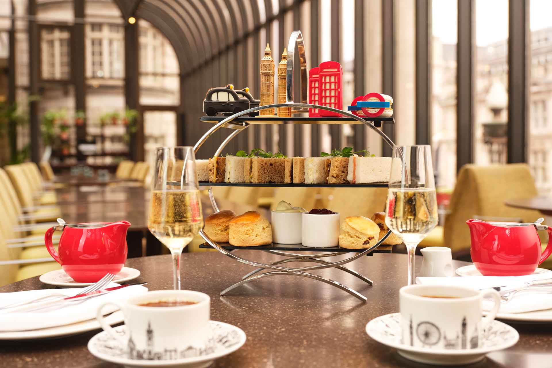 Tray of afternoon tea dishes including sandwiches, scones and London-themed cakes.
