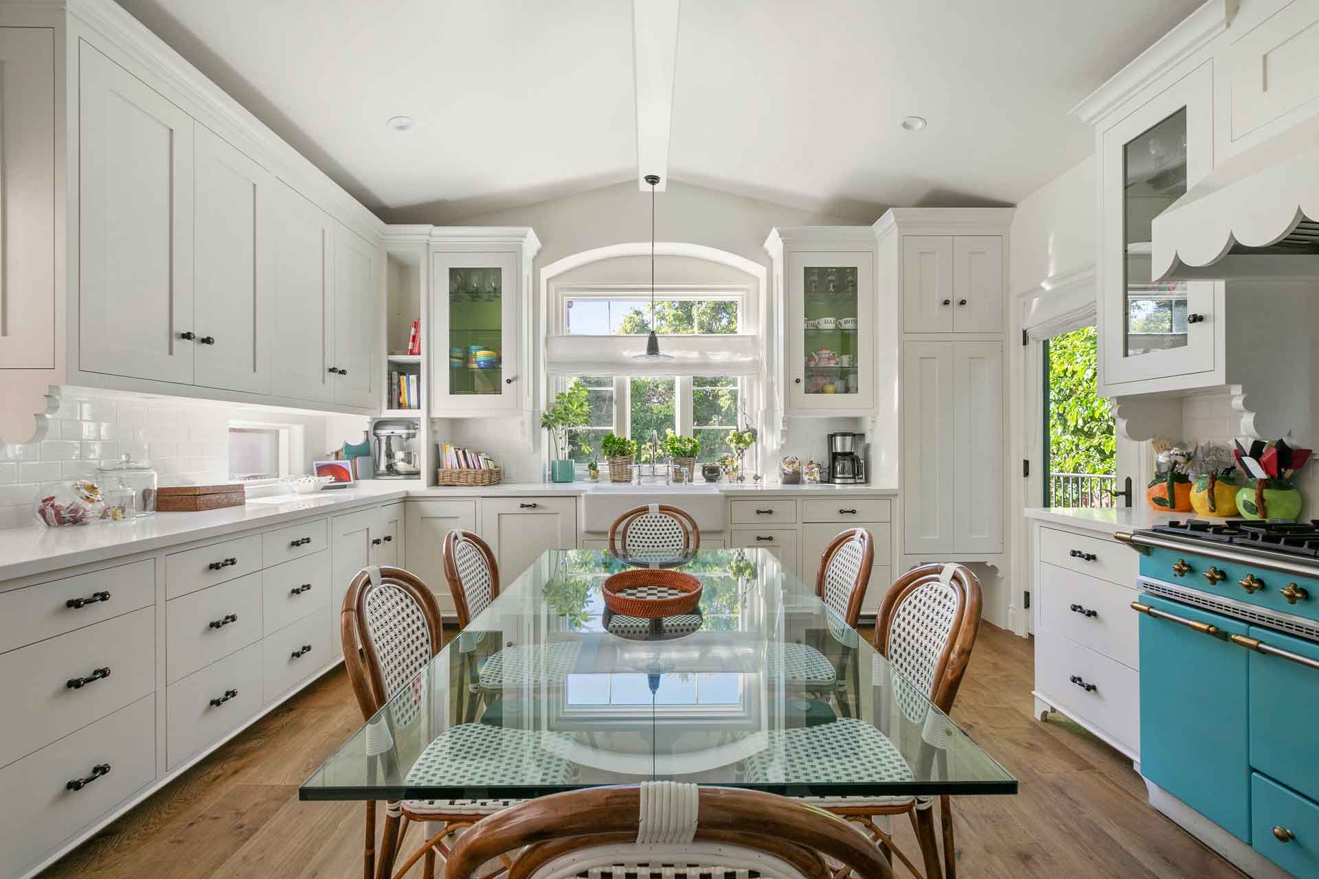 Cottage-style kitchen with white cabinetry and a central glass dining table