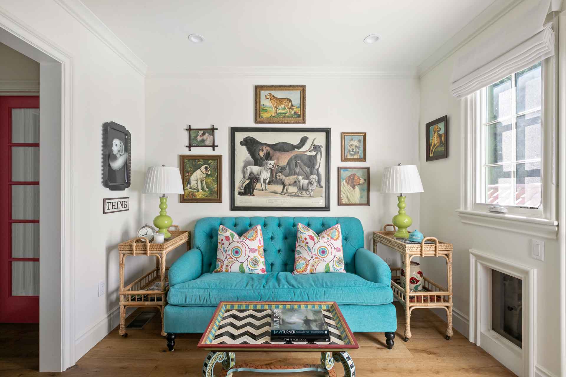 Living area with teal blue velvet sofa and gallery wall.