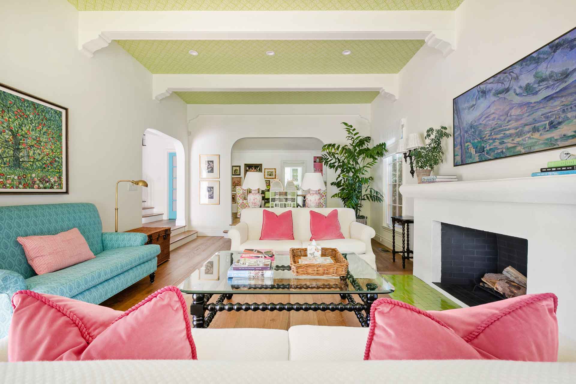 Living room with white sofas, pink cushions and a patterned green ceiling