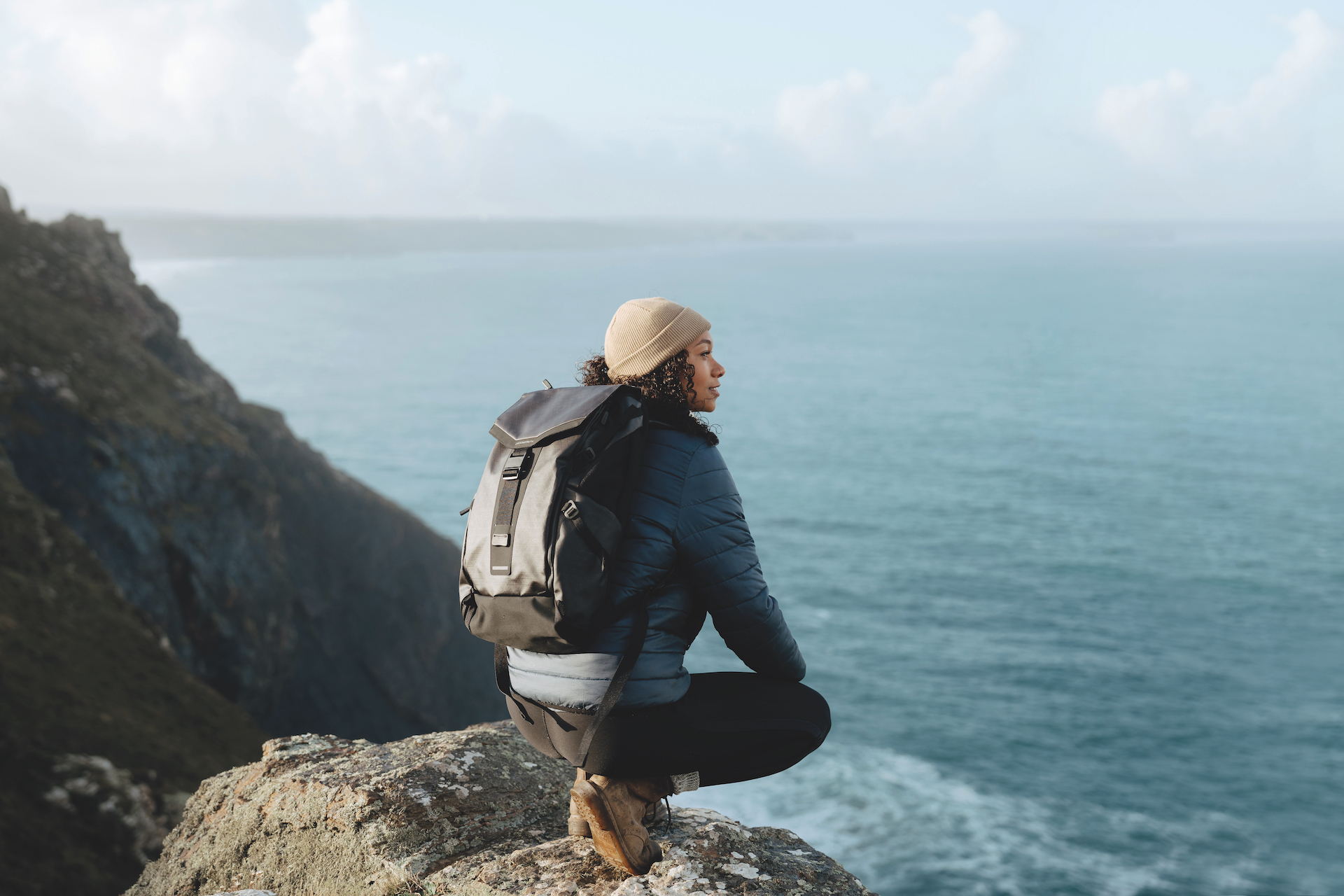 Groundtruth girl on cliff wearing black backpack