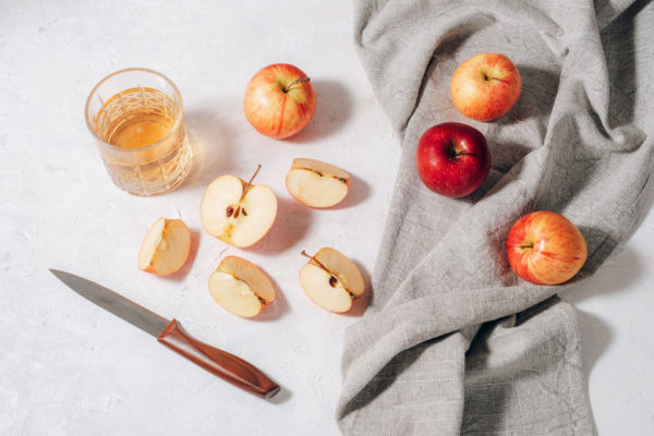 Apples on a white background with a cup of vinegar