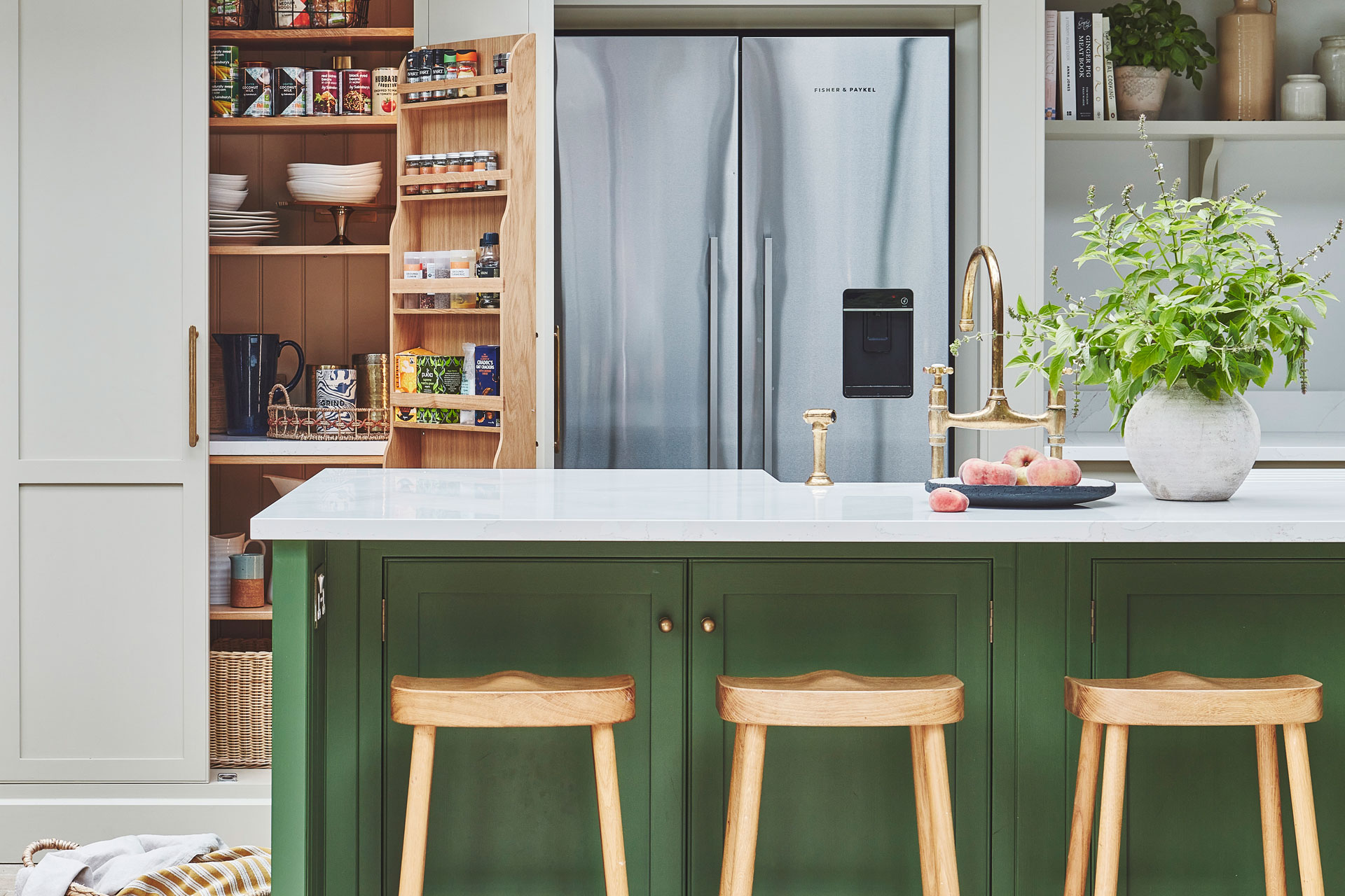 Forest green kitchen island with wooden stools and white countertops